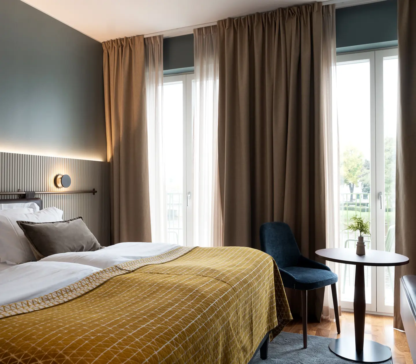 Comfortable hotel room with double bed, warm textiles and large windows