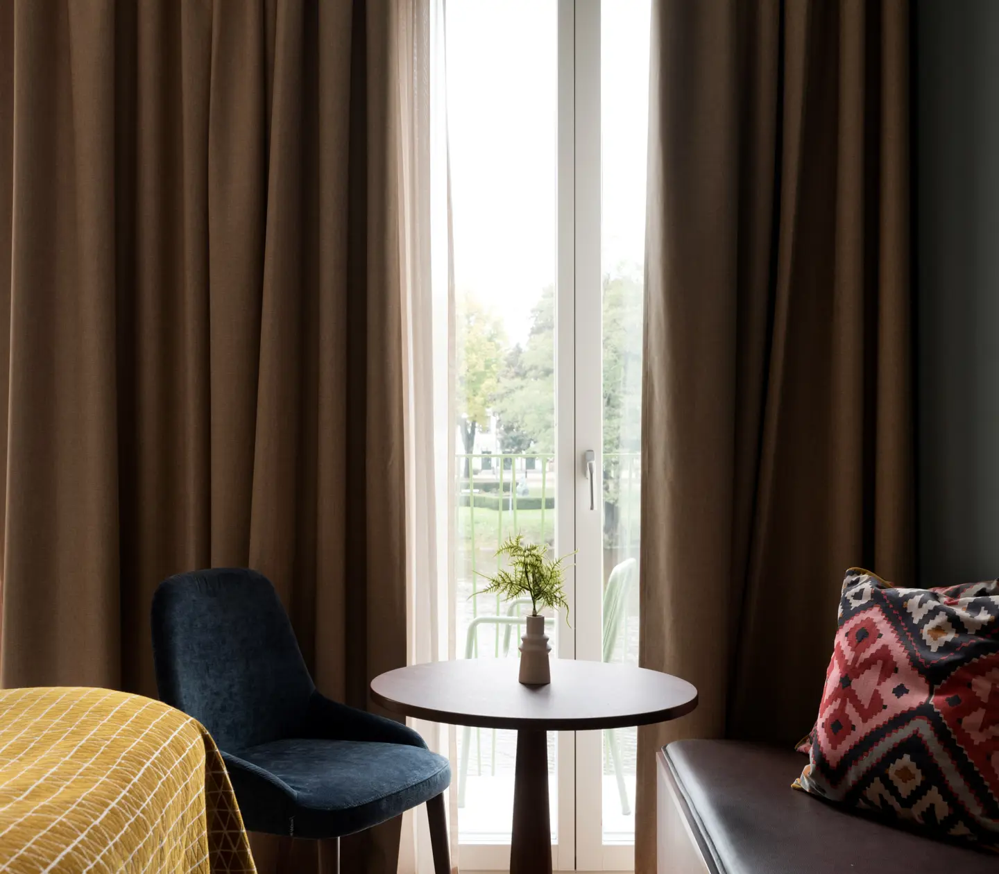 Comfortable hotel room with warm textiles and large windows facing the balcony