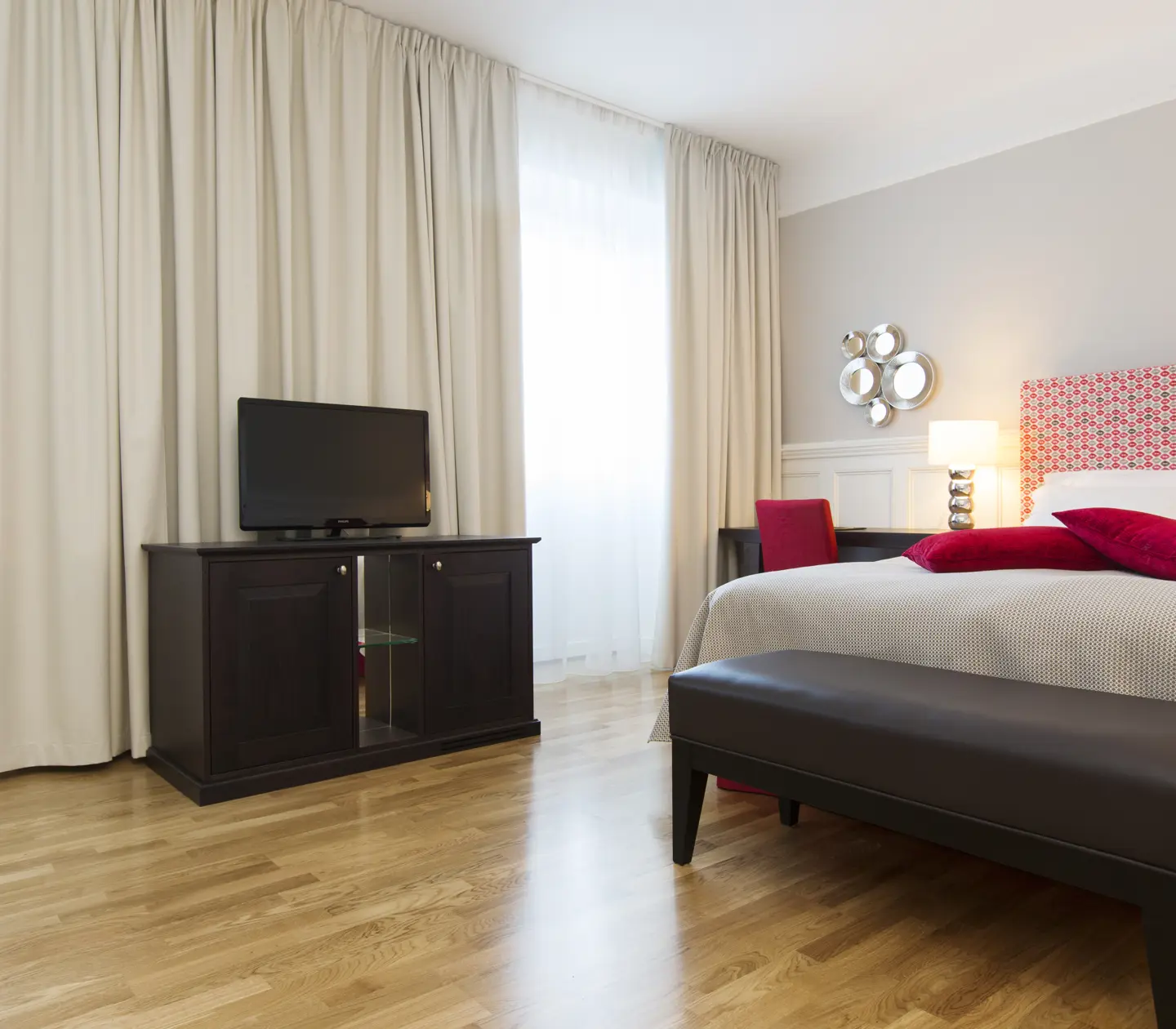 Bright hotel room with bed, desk and large windows