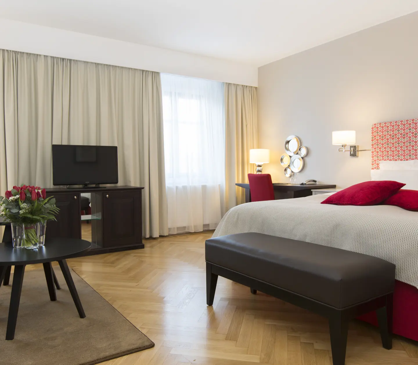 Bright hotel room with double bed, desk and TV
