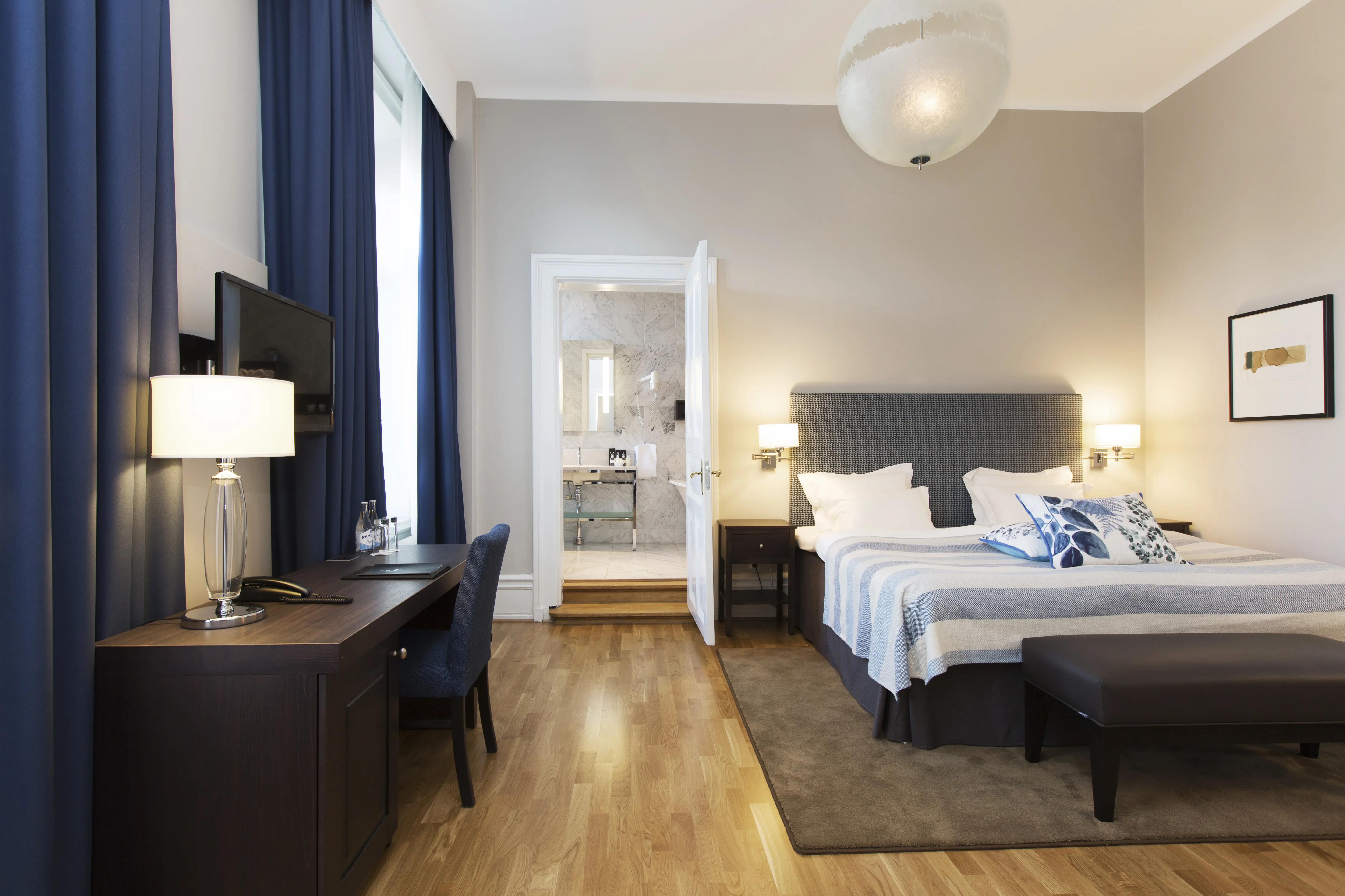 Bright suite with bed, desk and door to bathroom