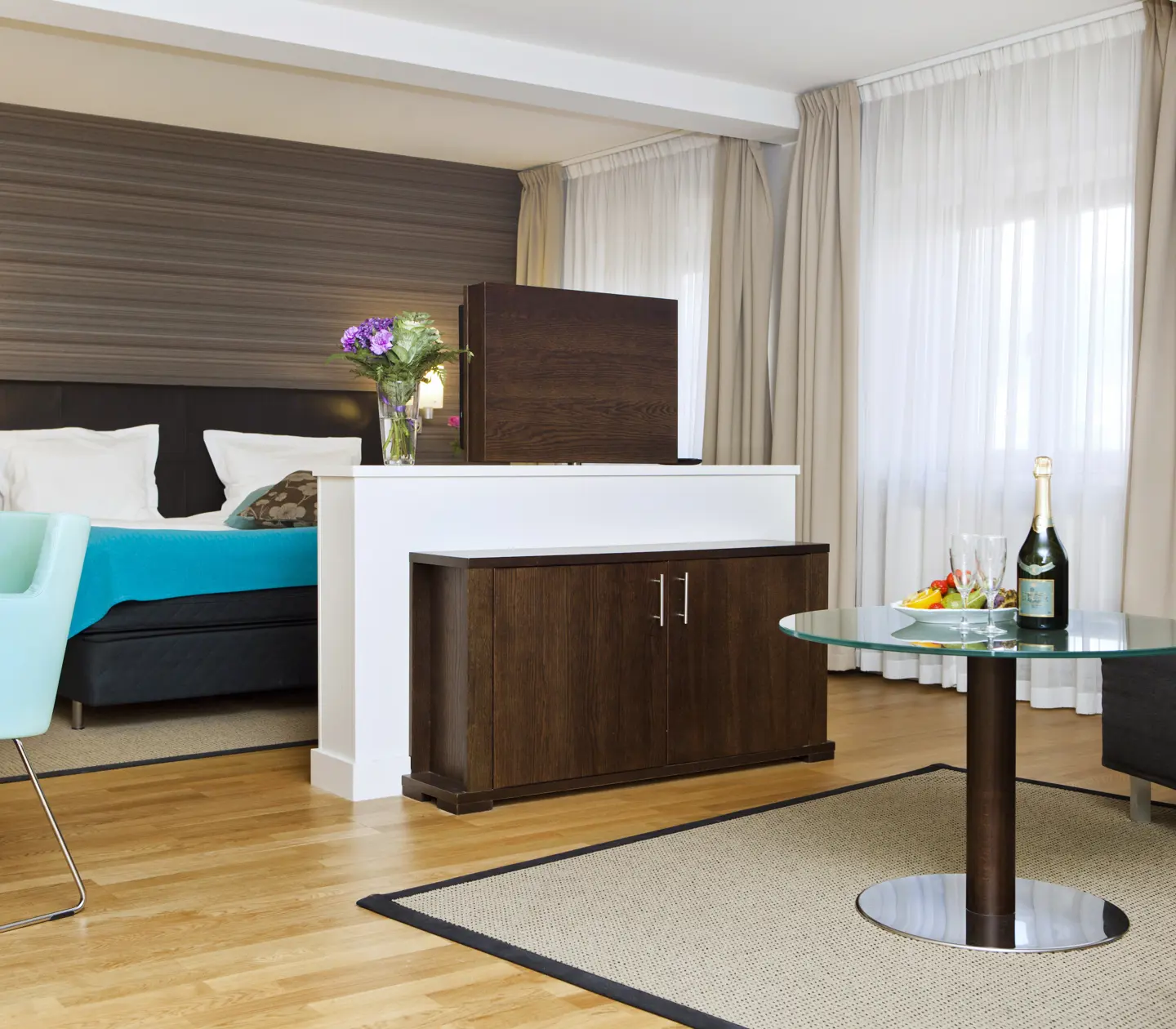 Suite with bed, TV and large windows