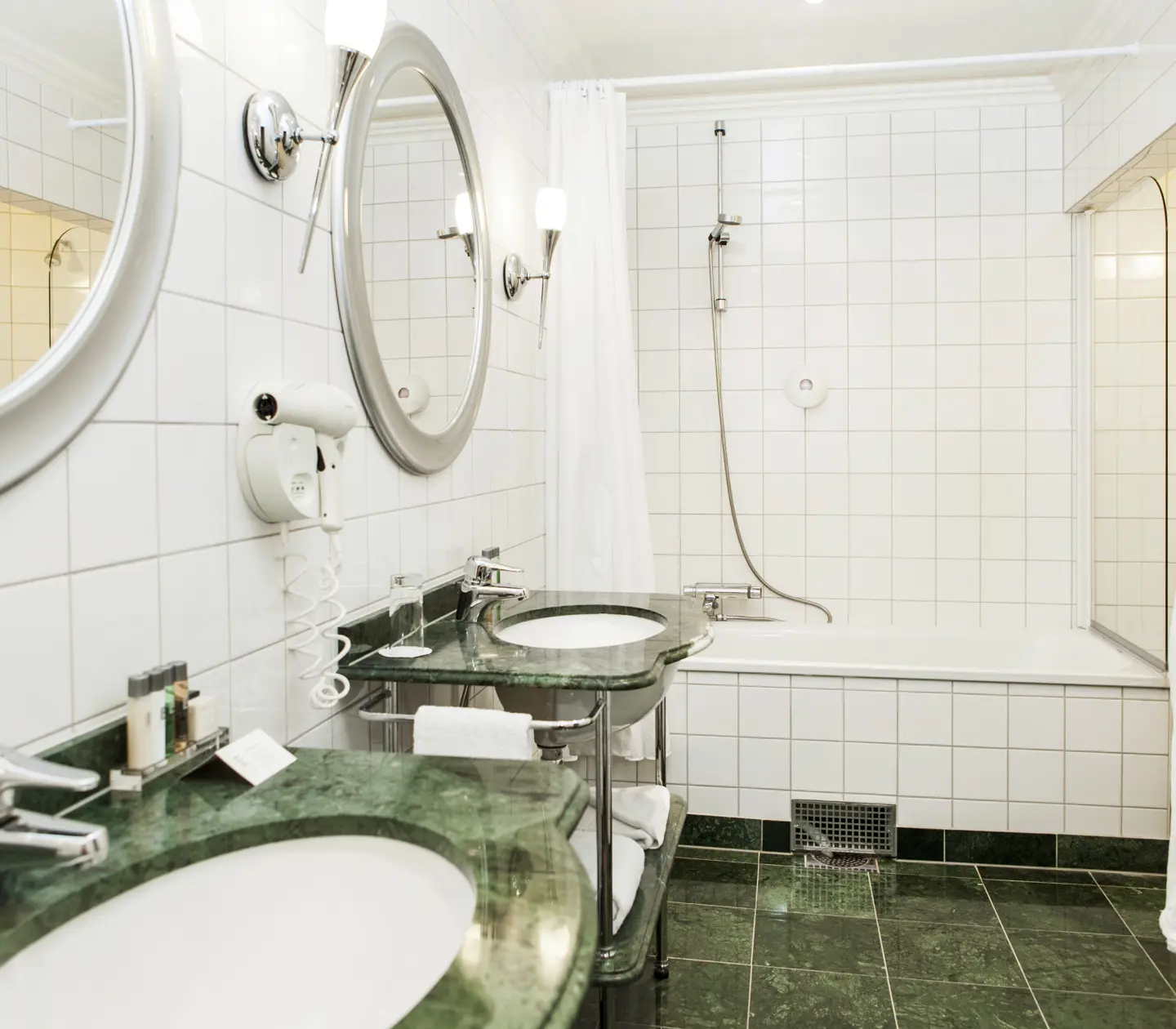 Badrum med två handfat, badkar och spegel