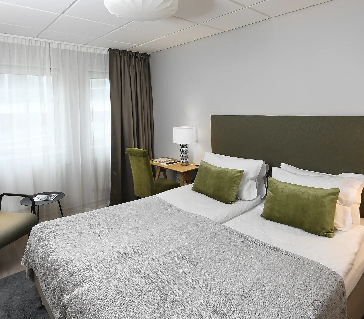 Bright hotel room with double bed, desk, armchair and window