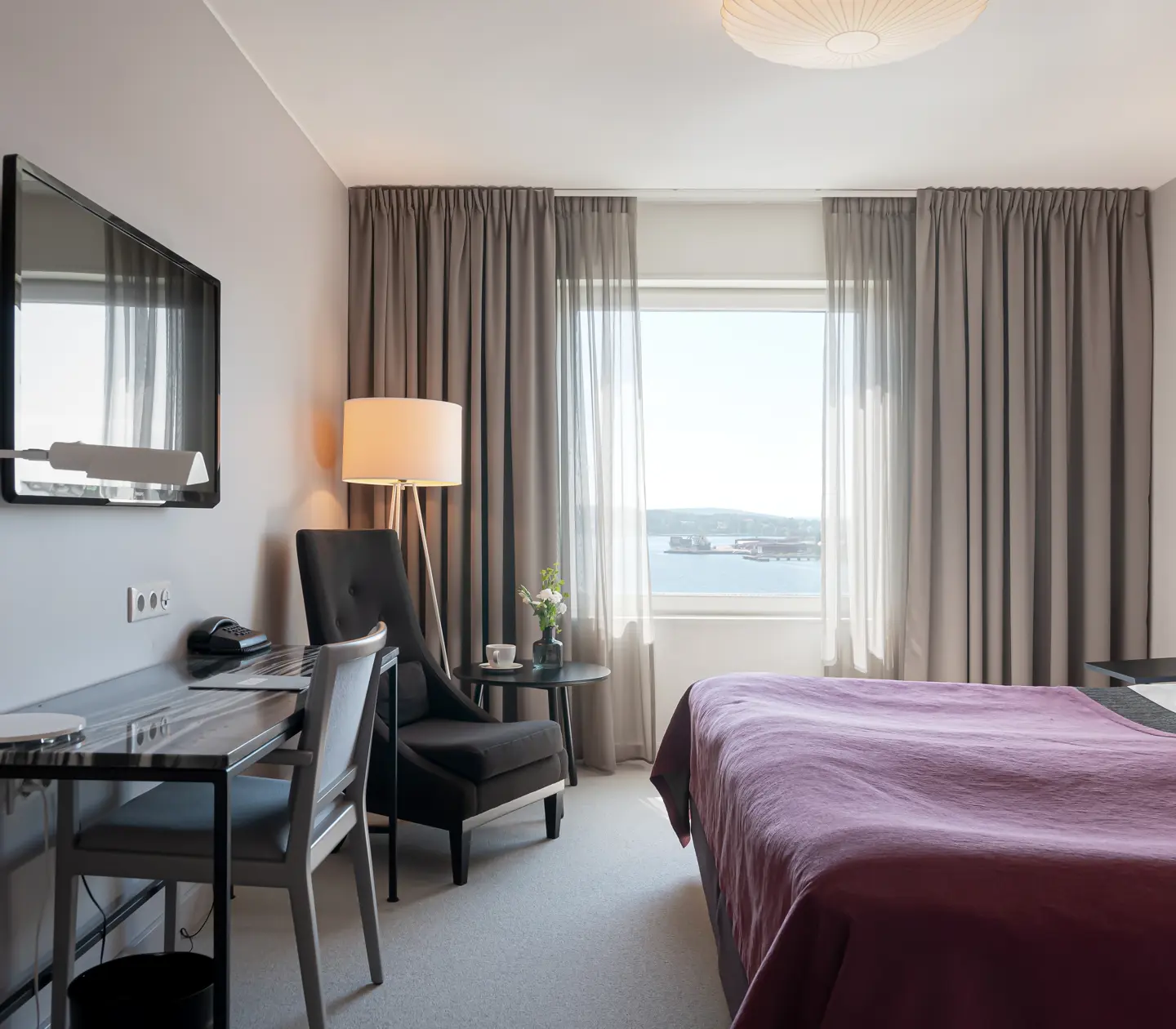 Hotel room with double bed, desk, armchair and window