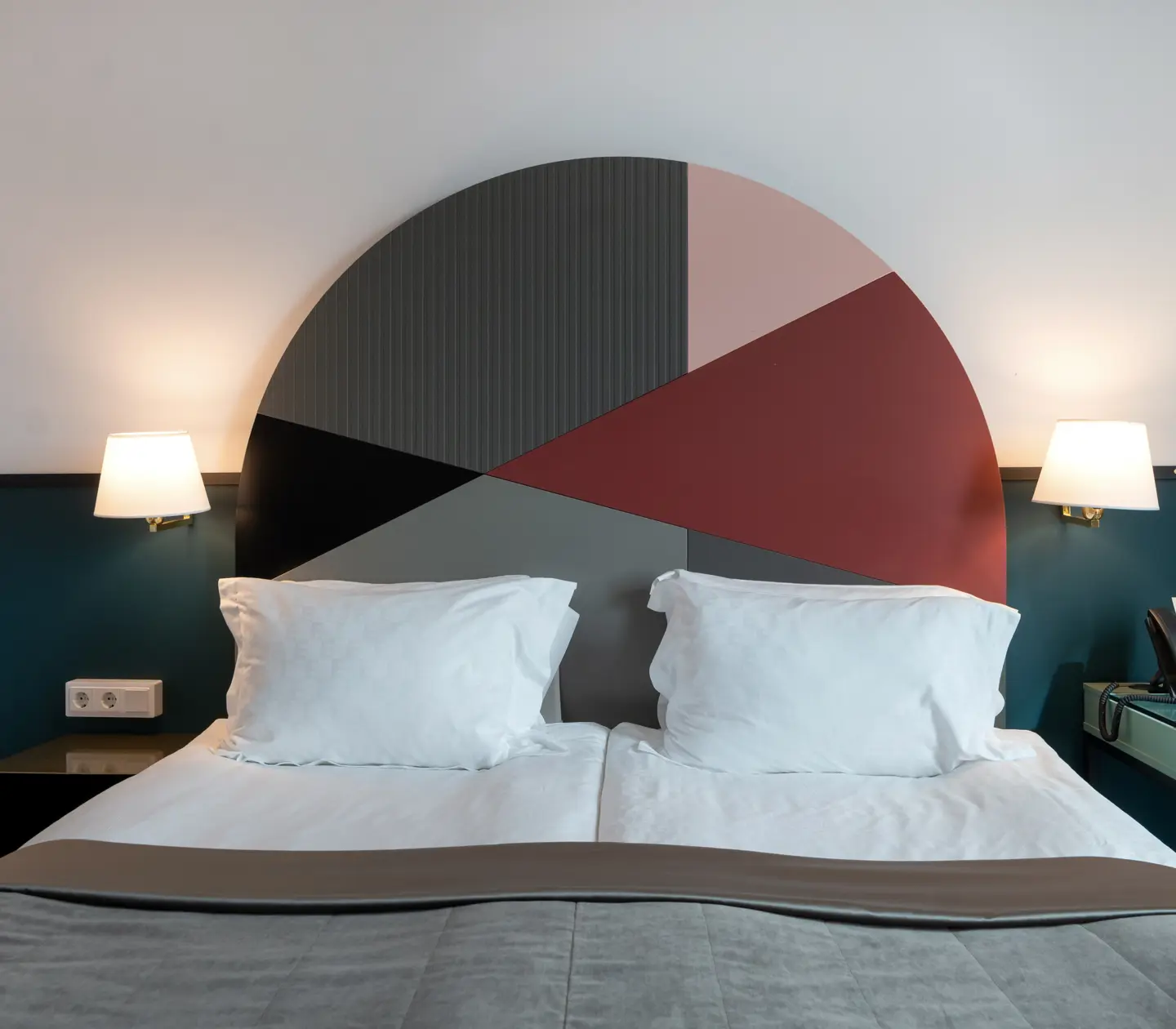 Bright hotel room with bed, colorful headboard and bedside lamp