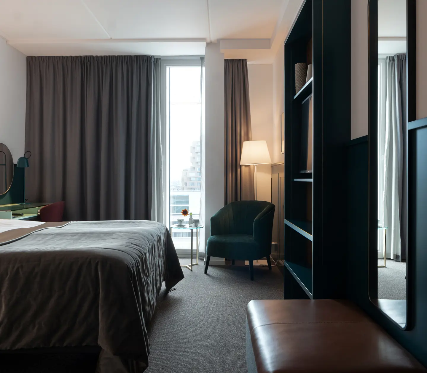 Bright hotel room with bed, armchair and bookshelf